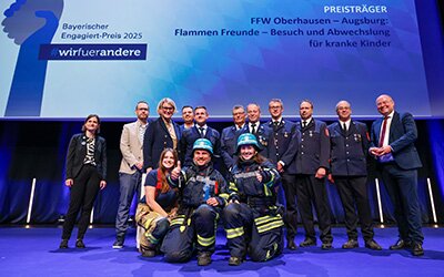 Vertreter*innen der Flammenfreunde, der KJF Klinik Josefinum und der Feuerwehr auf der Bühne